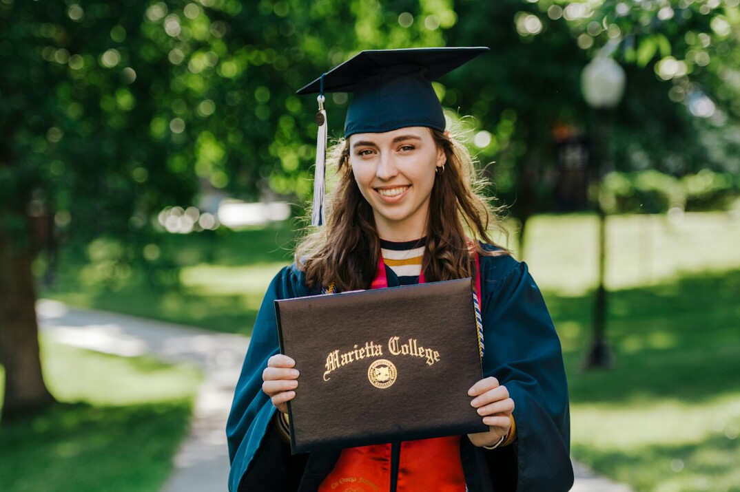 happy graduate holding laptop